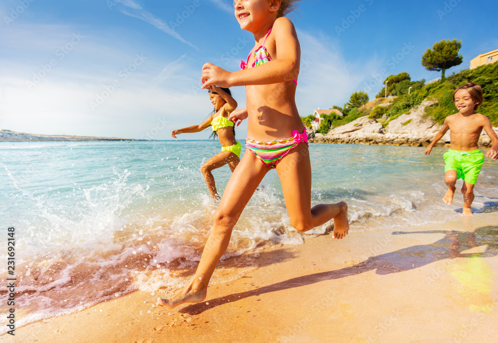 Wall mural Happy kids playing racing games on the beach