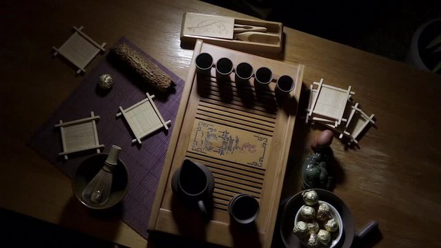 Wooden tea board with traditional Chinese cups and tipot for Chinese tea ceremony on the warm dark background.