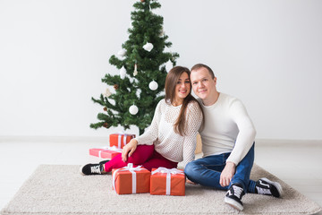 Obraz na płótnie Canvas Holidays and Christmas concept - Smiling modern young couple with Christmas gifts