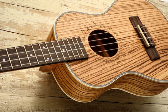 tenor ukulele made of zebrawood on aged wood background