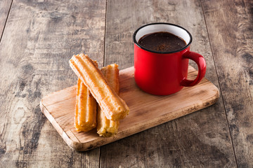 Hot chocolate with churros on wooden table.