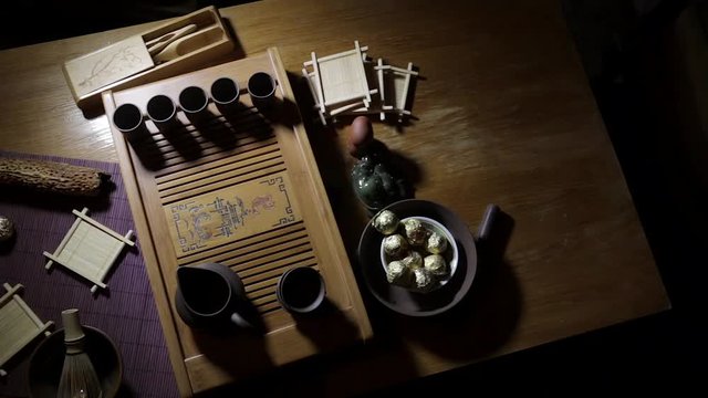 Wooden tea board with traditional Chinese cups and tipot for Chinese tea ceremony on the warm dark background.