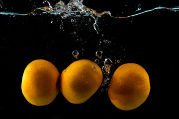 Fototapeta na wymiar Three ripe clementine in water splash on black