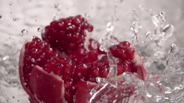 Falling splitted pomegranate into the water . Slow motion