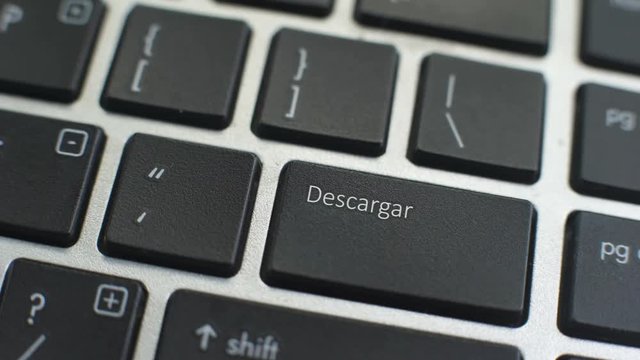 Download in Spanish button on computer keyboard, female hand fingers press key