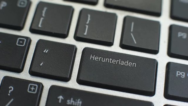 Download in German button on computer keyboard, female hand fingers press key