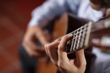 Close up of guitarist hand on classical guitar. Selective focus, shallow depth of field. - obrazy, fototapety, plakaty