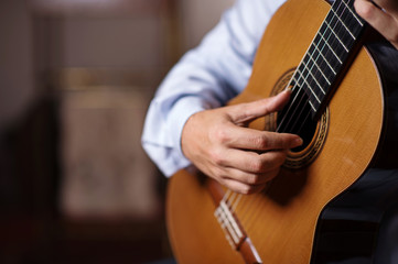 Close up of guitarist hand with long fingersnails on classical guitar. Selective focus, shallow...