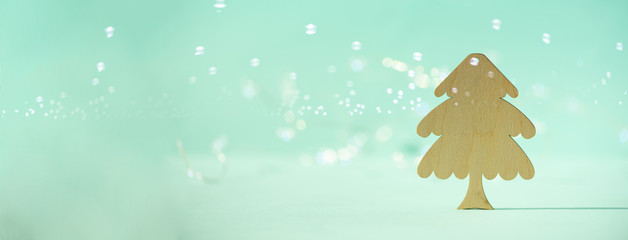 Greeting card in minimal style. Wooden Christmas tree on blue background with copy space, lights...