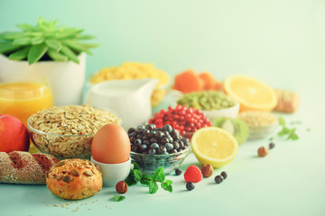 Delicious breakfast ingredients. Soft boiled egg, oat flakes, nuts, fruits, berries, milk, yogurt, orange, banana, peach on blue background.