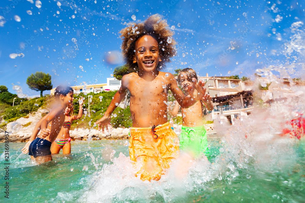 Wall mural african boy playing with friends in shallow water