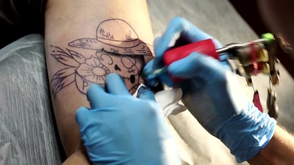 Needle tattoo machines inject a black ink into the skin of a man. Tattoo art on body. Makes a tattoo. Professional tattooist working tattooing in studio. Close-up.