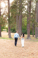 Fototapeta premium Man and woman walk on fallen leaves in forest or park