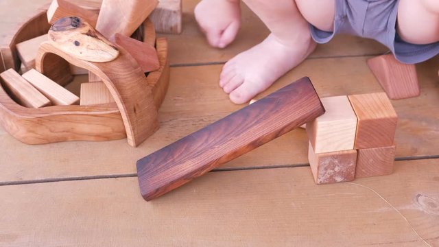 Little boy pushes a wooden car from the slide.