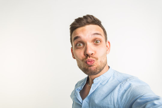 Close up portrait of a cheerful bearded man taking selfie over white background