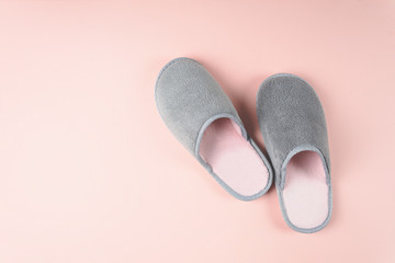 Gray and pink home slippers on a pastel paper background. Top view. Copy space. Toned - obrazy, fototapety, plakaty