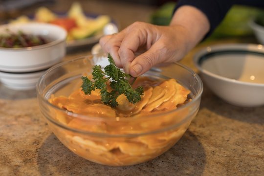 Woman garnishing coriander on food in kitchen