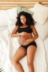 Naklejka premium High angle view of pregnant woman sleeping on the bed