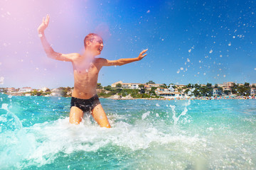 Teenage boy splashing and playing in shallow water