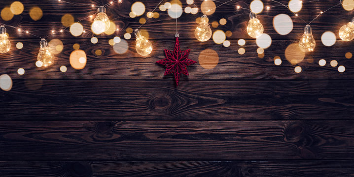 Empty, dark wooden background illuminated by retro light bulbs, with copy space 