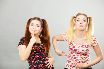 Two cheerful teenage woman holding their stomach