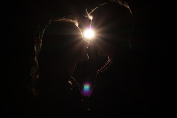 black background, silhouette of couples, heads, between them a light, a ray of light unfinished...