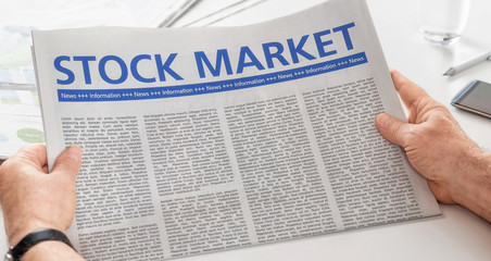 Man reading newspaper with the headline Stock Market
