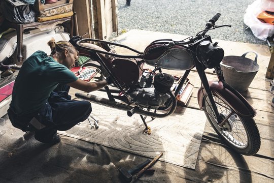 Female mechanic repairing motorcycle in workshop