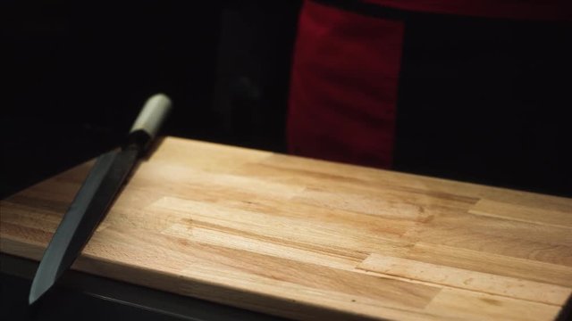 Close-up of knife on cutting board. Wooden board and knife ready to cook on dark background. Items for cutting and cooking