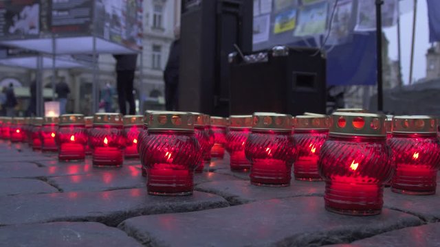 A lot of memorial Candles in Red Victorian Glass Candle Holder on coblestone road.