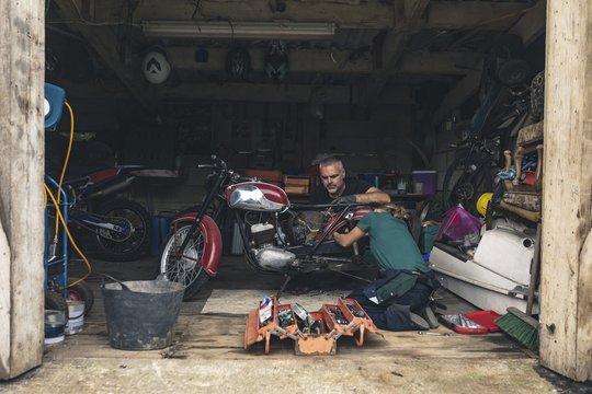 Mechanic repairing motorbike in garage - Powered by Adobe