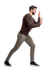 A bearded fit man in casual pants presses his hands over an invisible object in order to move it.