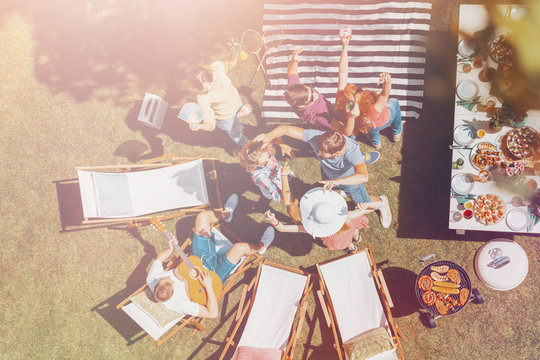 High angle on happy people dancing next to sunbeds and table with food in the garden