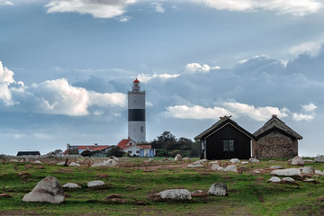 Fototapeta na wymiar Picture of old scandinavian lighthouse and abandoned wooden houses with cloudy sky