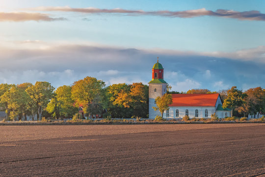 Picture of old scandinavian style church in the field and sunset sun