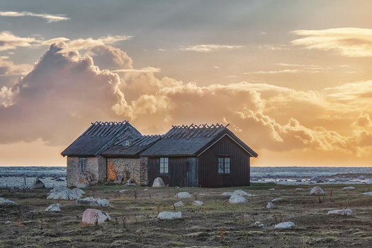 Picture of old and abandoned wooden scandinavian style houses with sunset at the background