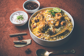 Delicious spicy chicken biryani in bowl over moody background, it’s a popular Indian and Pakistani food.