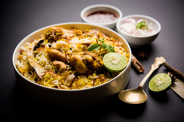 Delicious spicy chicken biryani in bowl over moody background, it’s a popular Indian and...