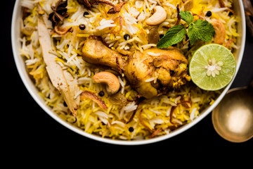 Obraz na płótnie Canvas Delicious spicy chicken biryani in bowl over moody background, it’s a popular Indian and Pakistani food.