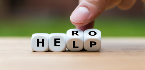 Hand is turning a dice and changes the word "help" to "hero"