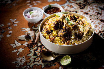 mutton or lamb biriyani with basmati rice, served in a bowl over moody background.