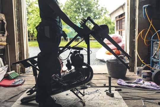 Female mechanic repairing motorbike in garage - Powered by Adobe