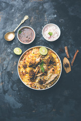 mutton or lamb biriyani with basmati rice, served in a bowl over moody background.