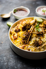 mutton or lamb biriyani with basmati rice, served in a bowl over moody background.