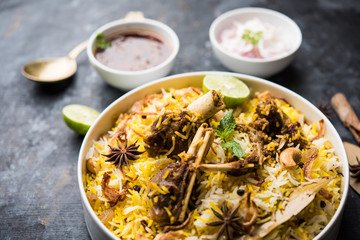 mutton or lamb biriyani with basmati rice, served in a bowl over moody background.