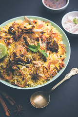 mutton or lamb biriyani with basmati rice, served in a bowl over moody background.