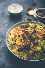mutton or lamb biriyani with basmati rice, served in a bowl over moody background.