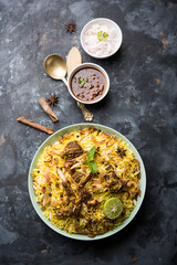 mutton or lamb biriyani with basmati rice, served in a bowl over moody background.