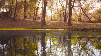 Autumn landscape, lake in the park, unrecognizable people on the background.