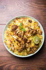 mutton or lamb biriyani with basmati rice, served in a bowl over moody background.